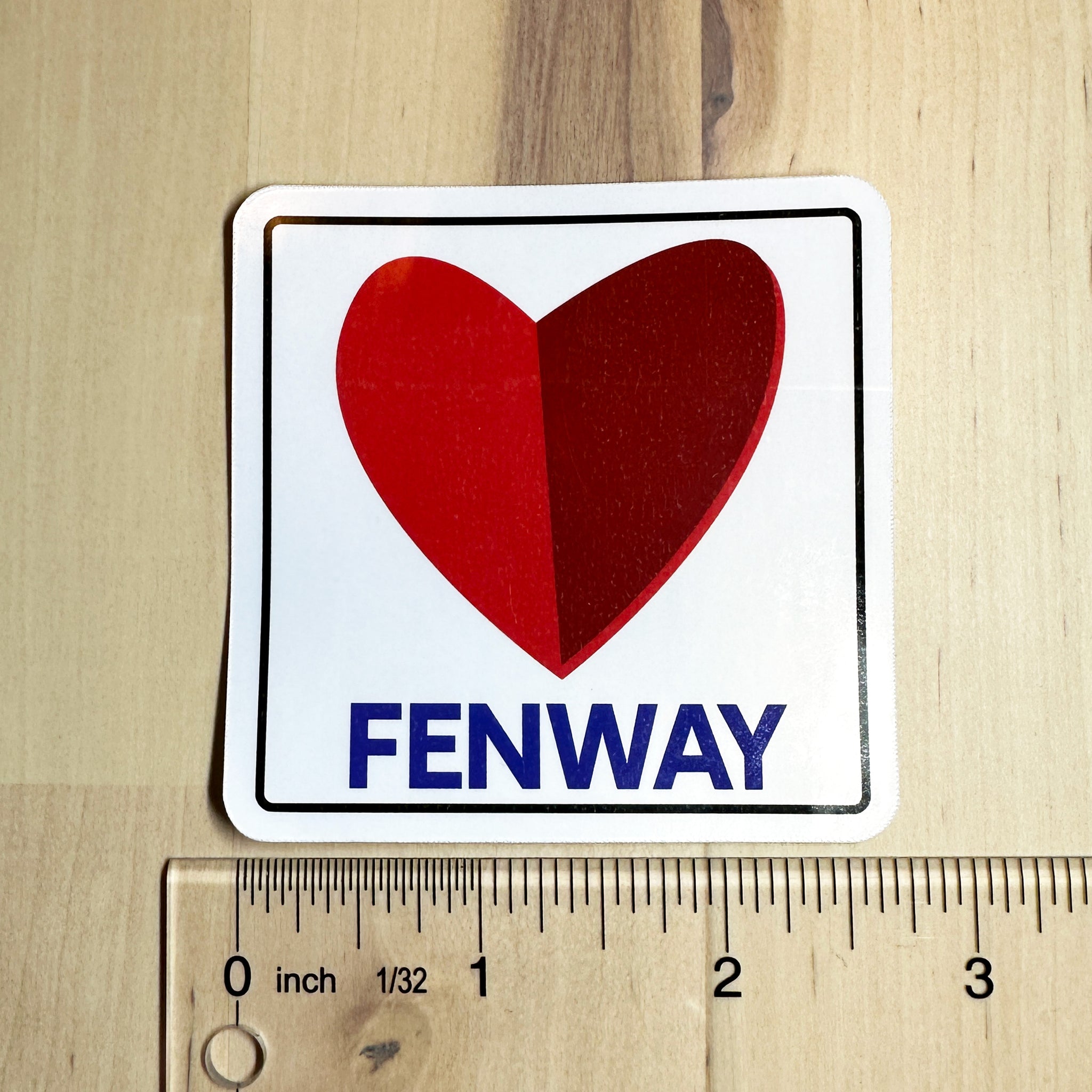 photo of a square vinyl sticker with the word FENWAY and a heart in the style of the boston citgo sign with a ruler