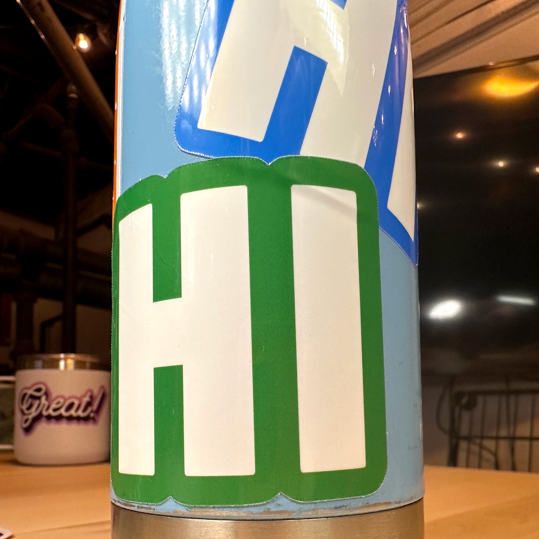 photo of square vinyl sticker with the word HI in white with a green background on a metal water bottle