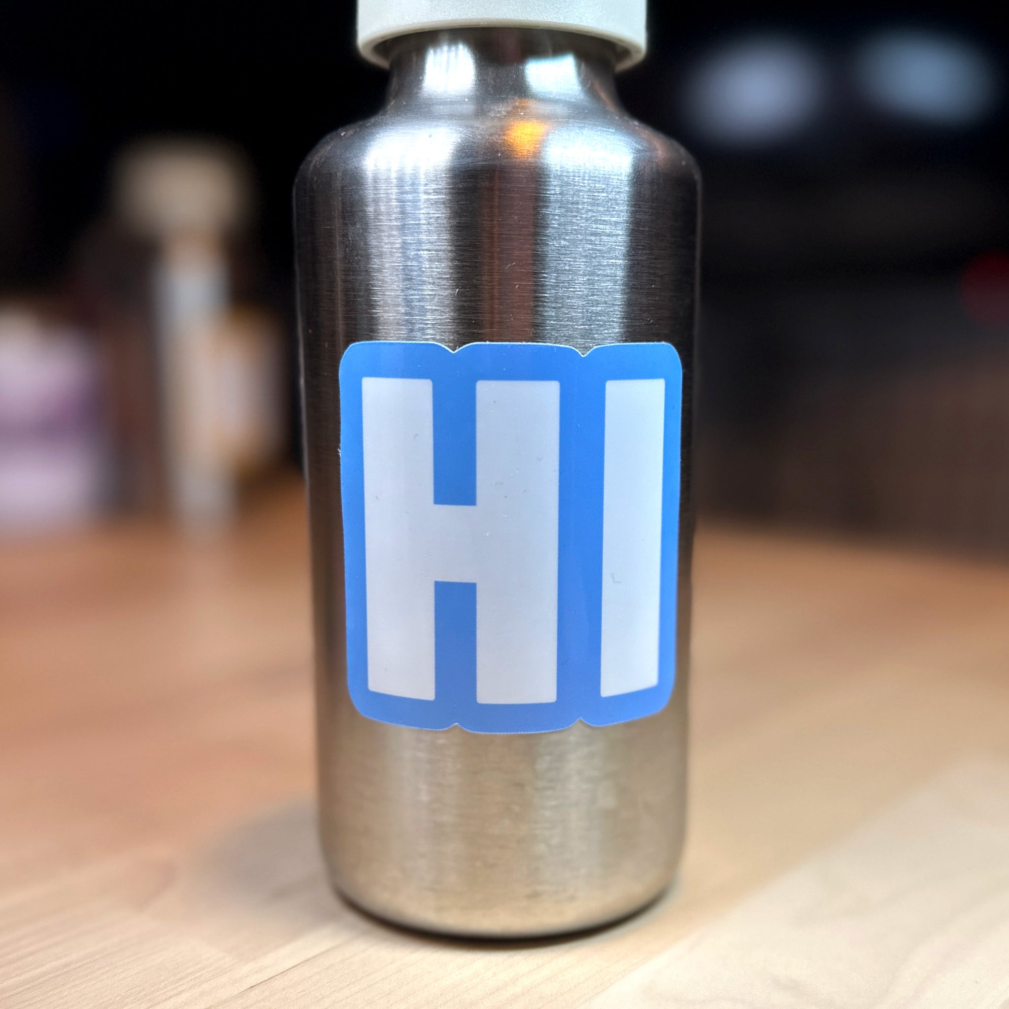 photo of square vinyl sticker with the word HI in white with a light blue background on a metal water bottle