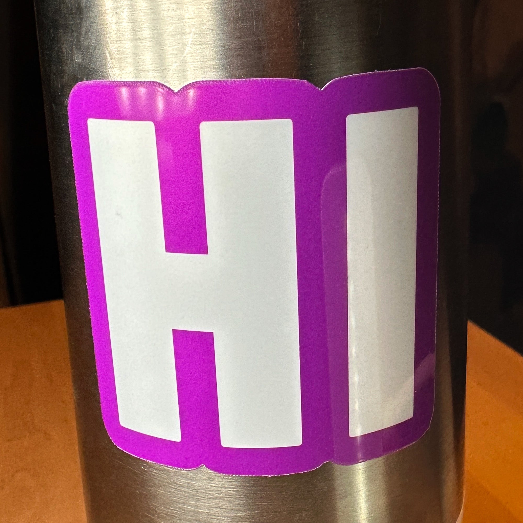 photo of square vinyl sticker with the word HI in white with a purple background on a metal water bottle