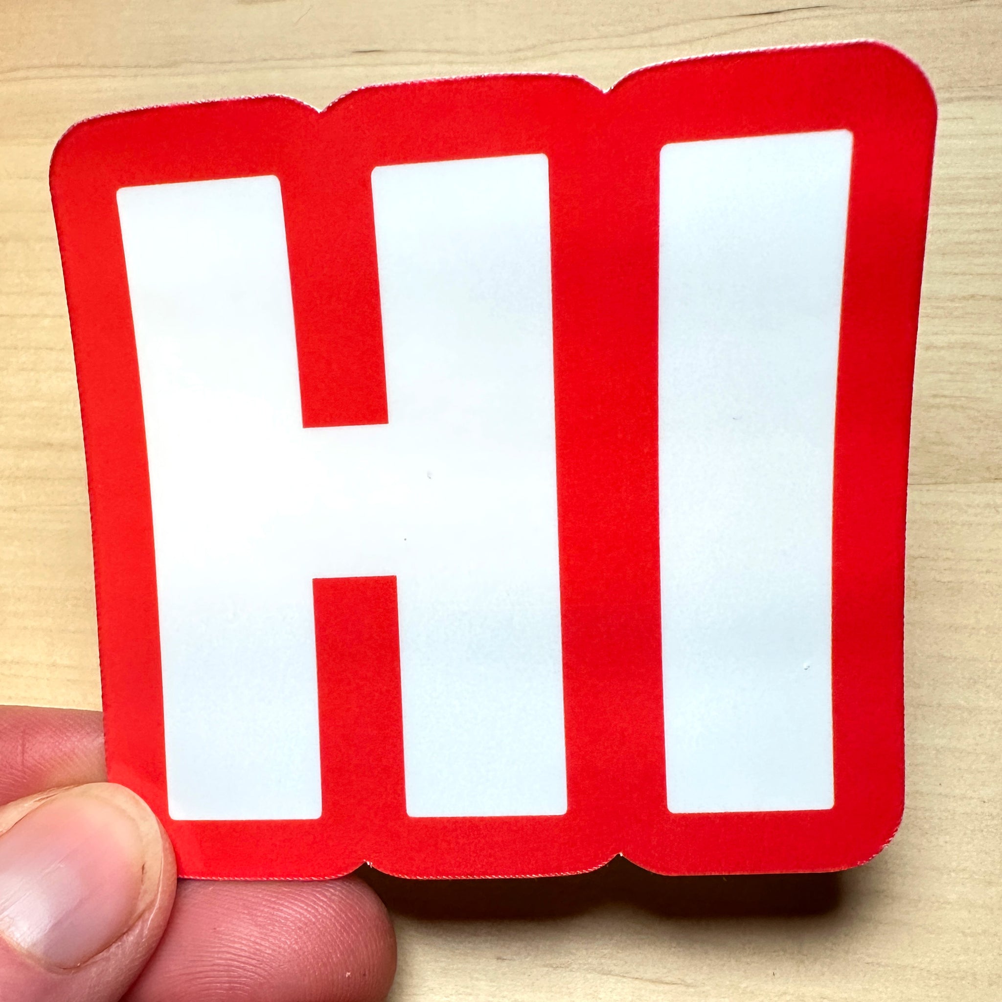 photo of square vinyl sticker with the word HI in white with a red background