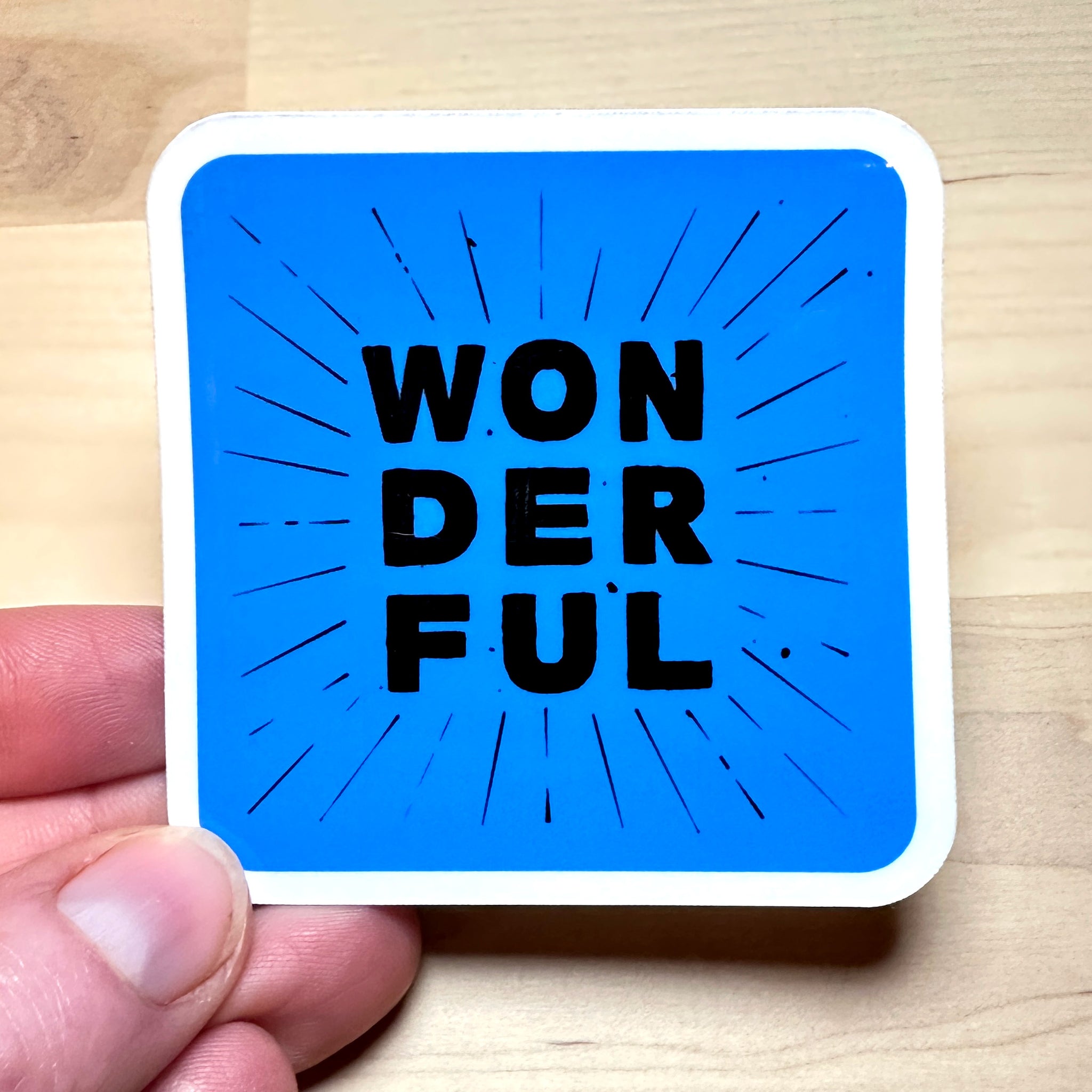 photo of waterproof vinyl sticker with the word wonderful in 3 layers of black text on blue background