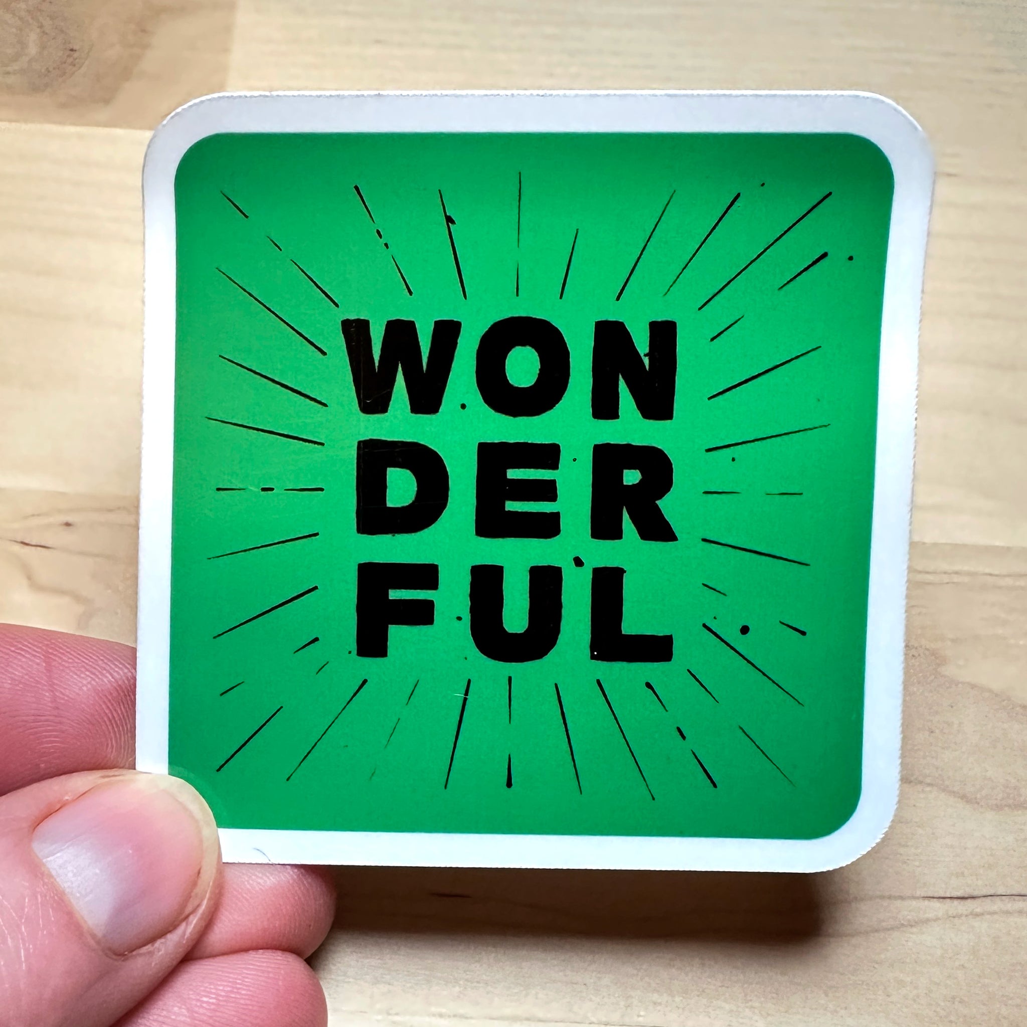 photo of waterproof vinyl sticker with the word wonderful in 3 layers of black text on green background