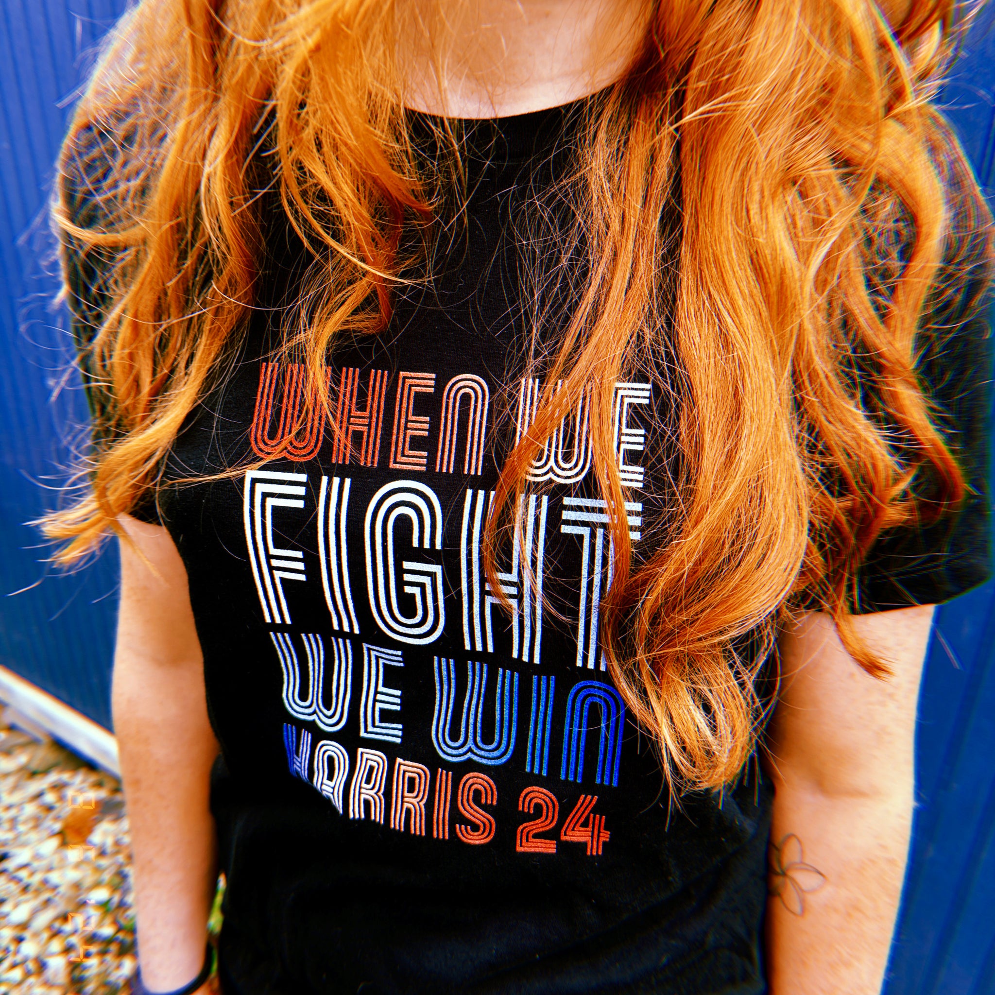 woman with red hair wearing black women shirt with when we fight we win harris 24 in red white and blue blended text