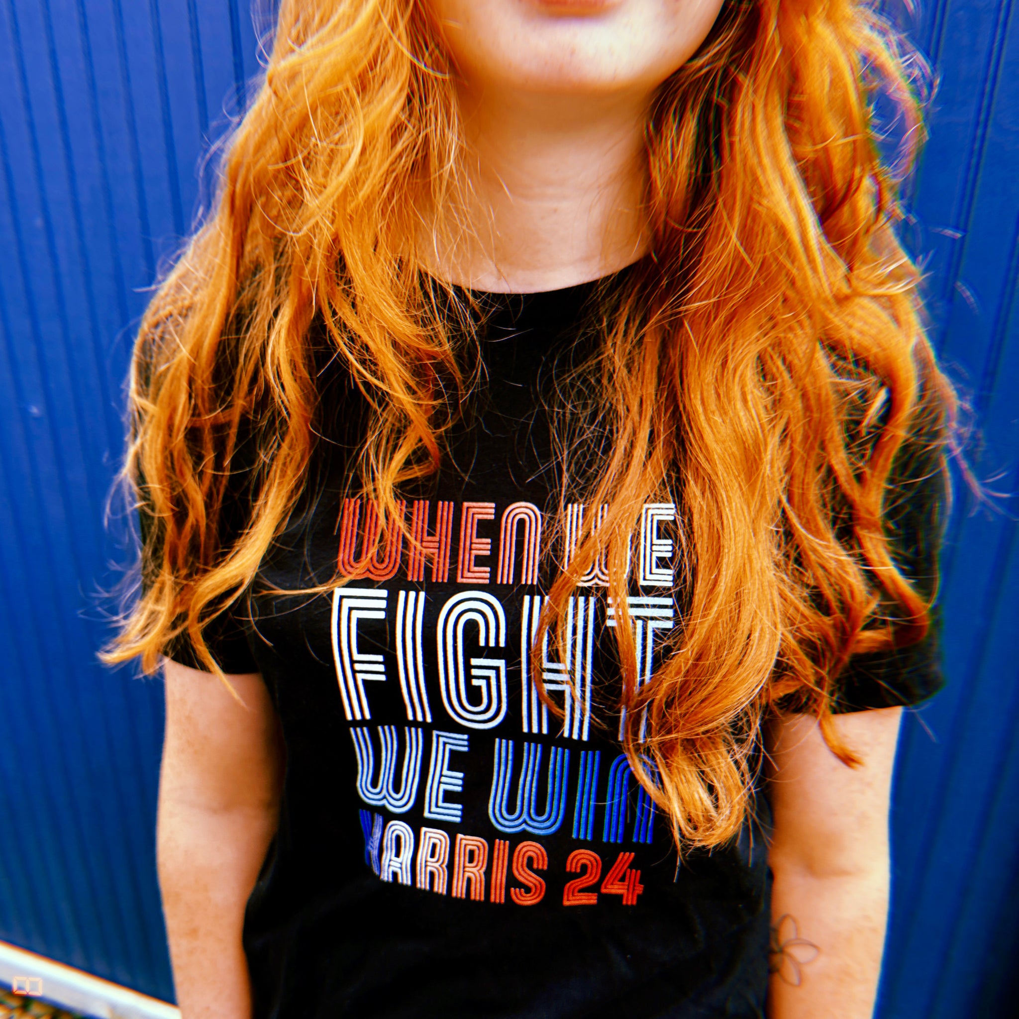 woman with red hair wearing black women shirt with when we fight we win harris 24 in red white and blue blended text