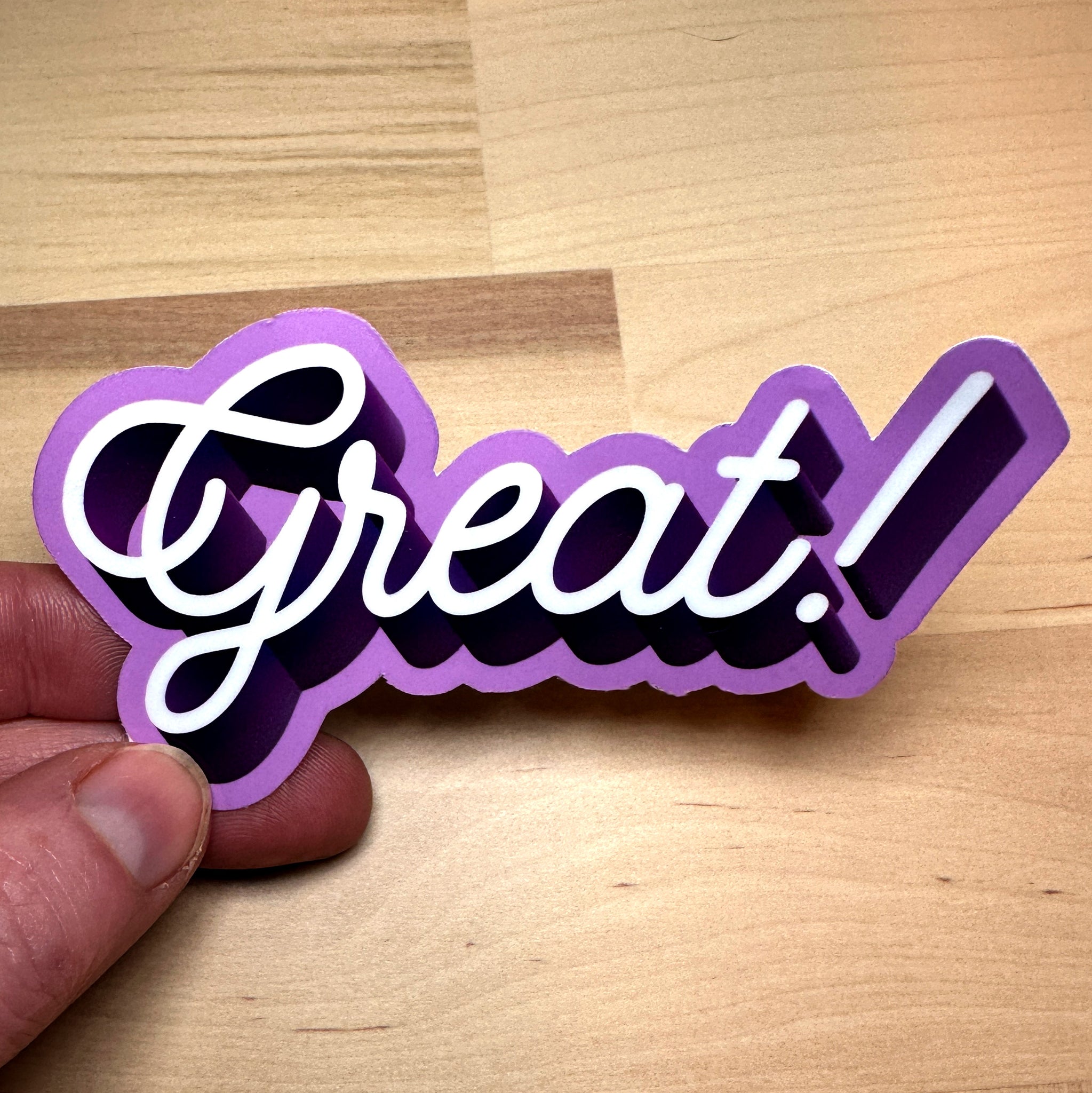 photo of a waterproof vinyl sticker with the word Great in white cursive with dark and light purple outline