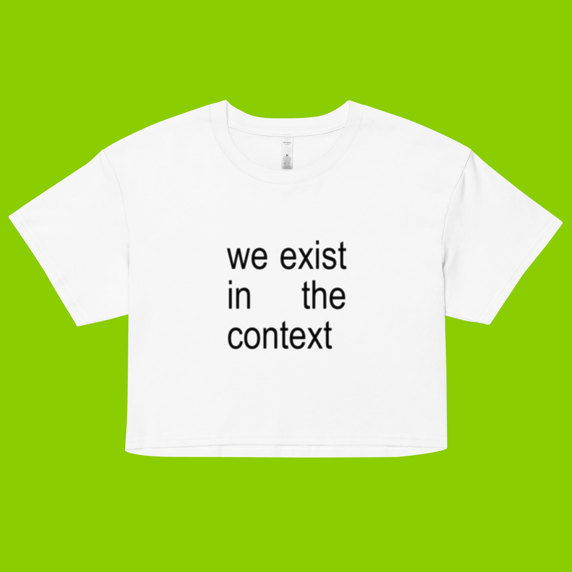 white women's crop top t-shirt with the phrase we exist in the context from kamala harris and charli xcx brat