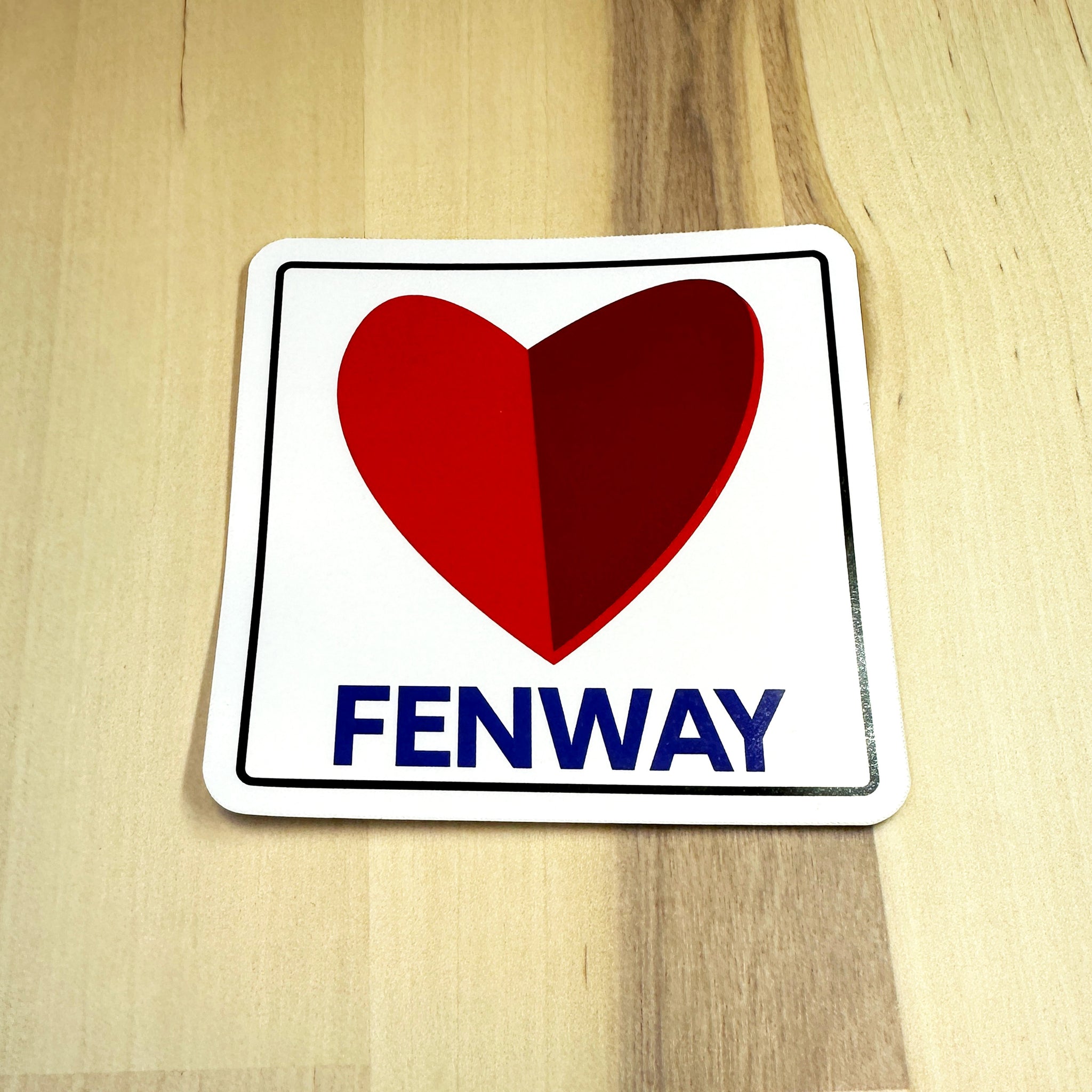 photo of a square vinyl sticker with the word FENWAY and a heart in the style of the boston citgo sign