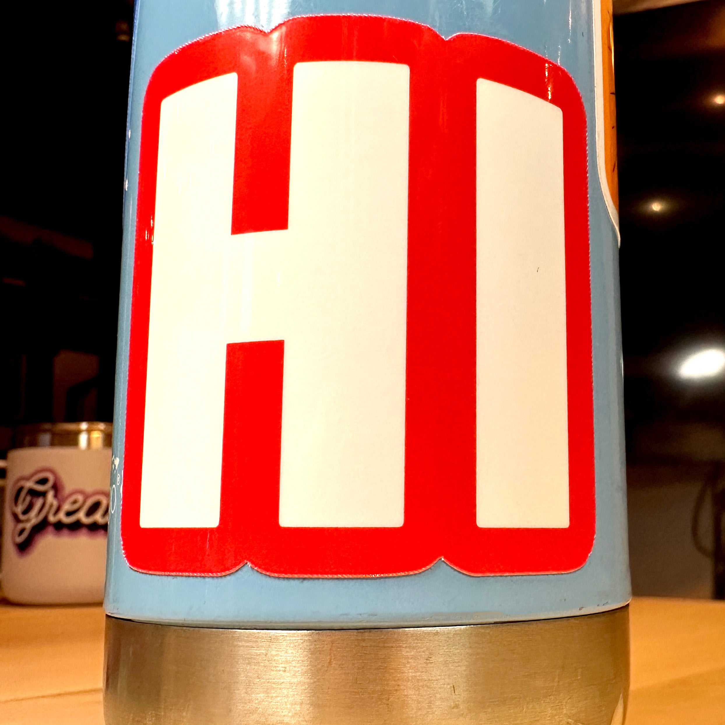 photo of square vinyl sticker with the word HI in white with a red background on a metal water bottle