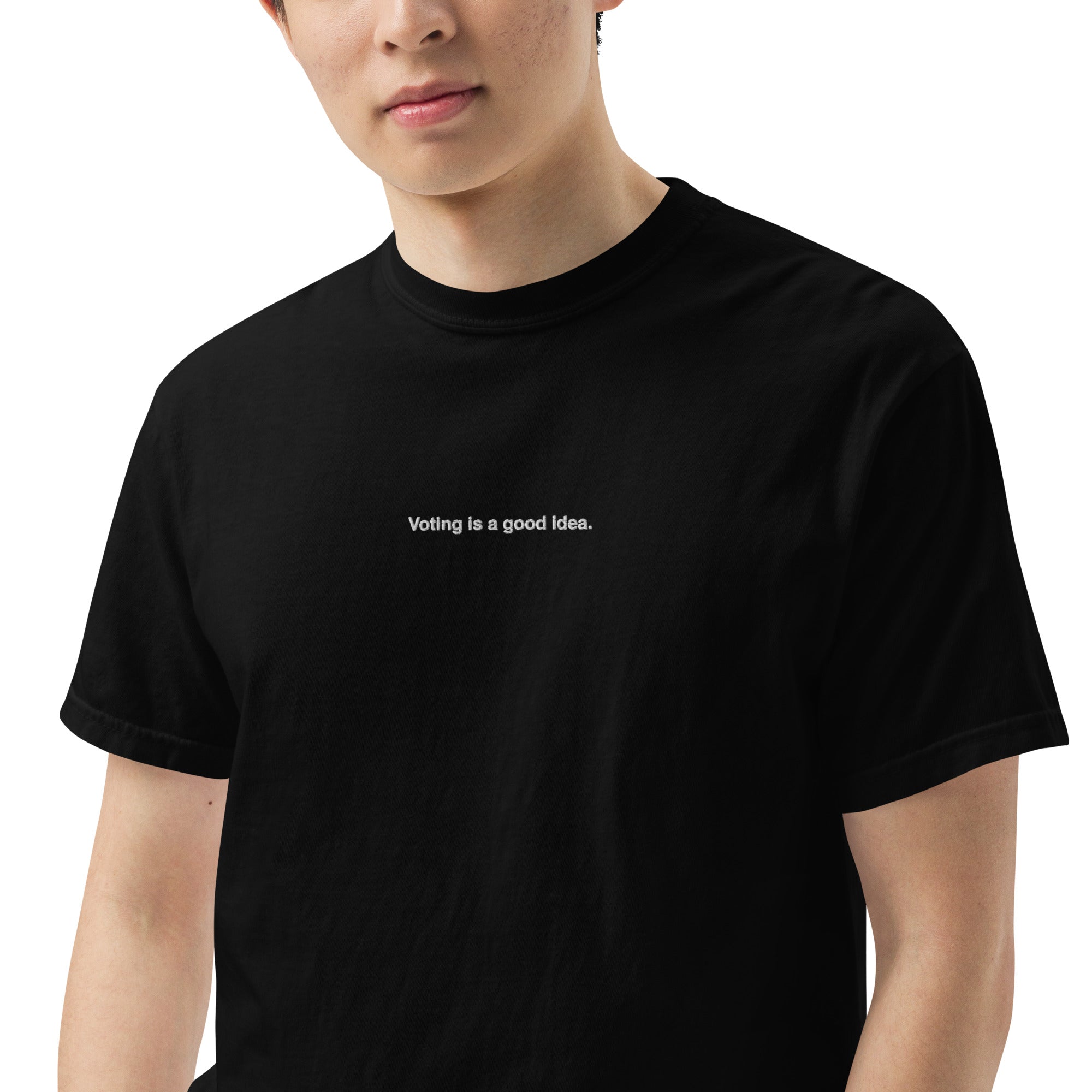 man wearing black heavyweight unisex t-shirt with the phrase, voting is a good idea, embroidered in white on the front