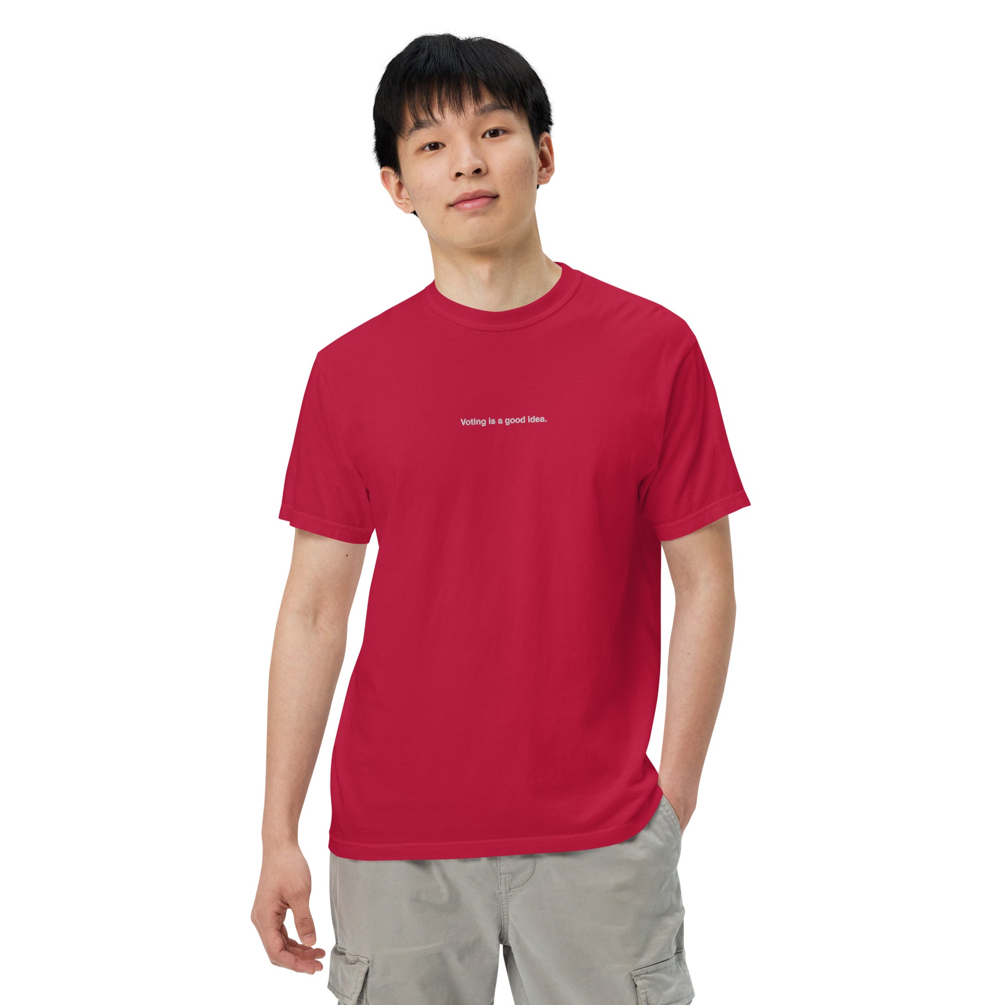 man wearing red heavyweight unisex t-shirt with the phrase, voting is a good idea, embroidered in white on the front