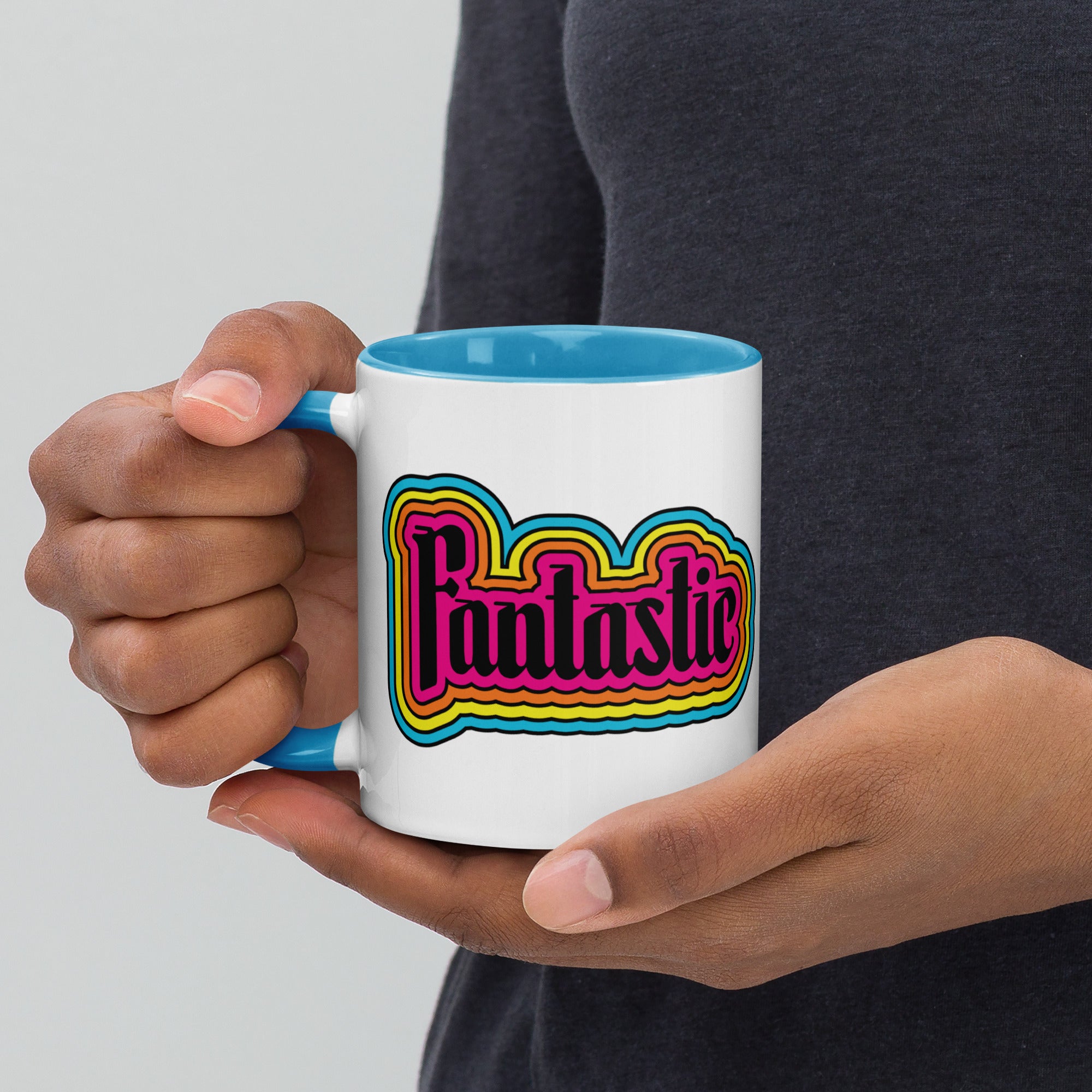 person holding 11 oz mug with the word fantastic with rainbow design around it