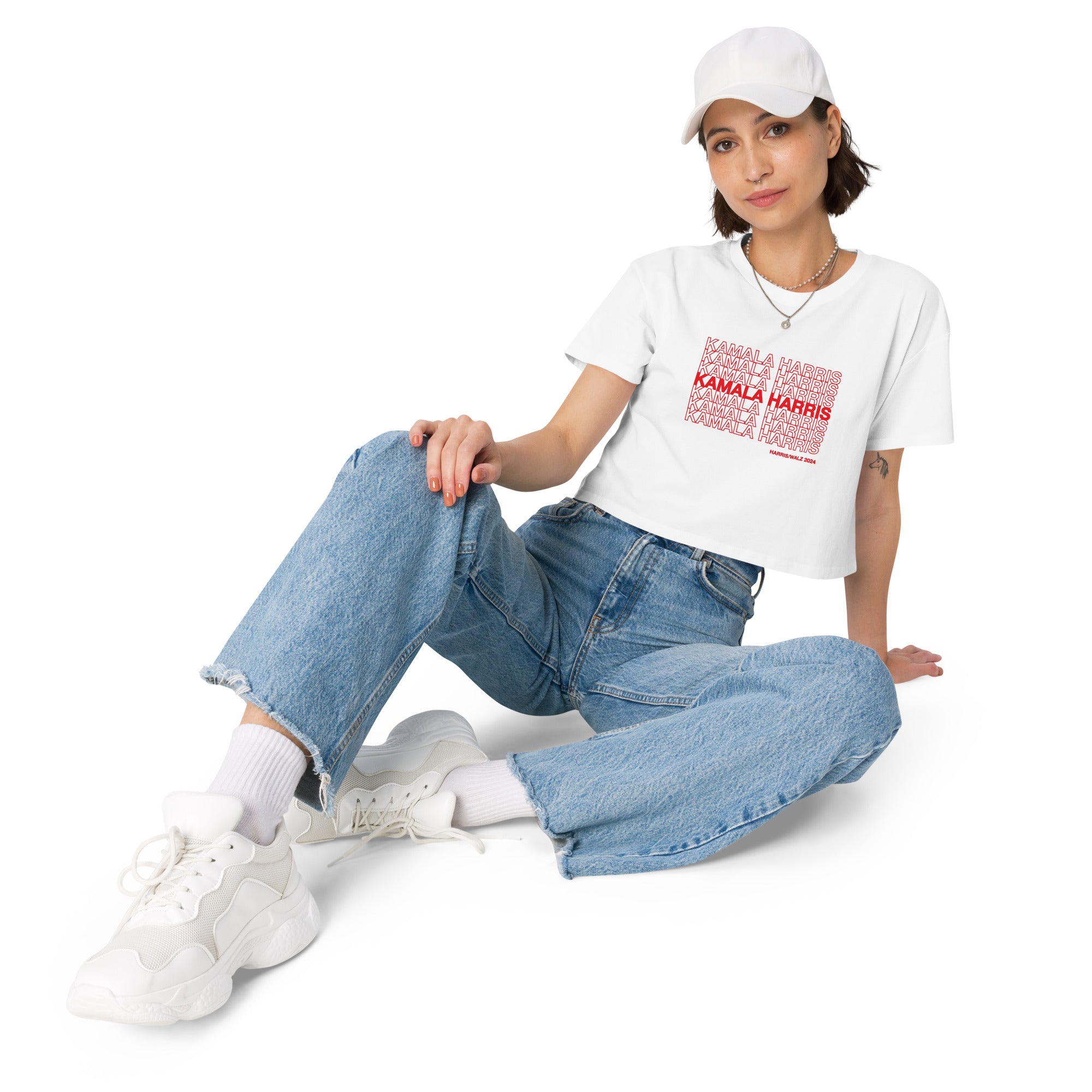 woman wearing White women's crop top t-shirt with red text saying "kamala Harris" in the classic plastic shopping bag design