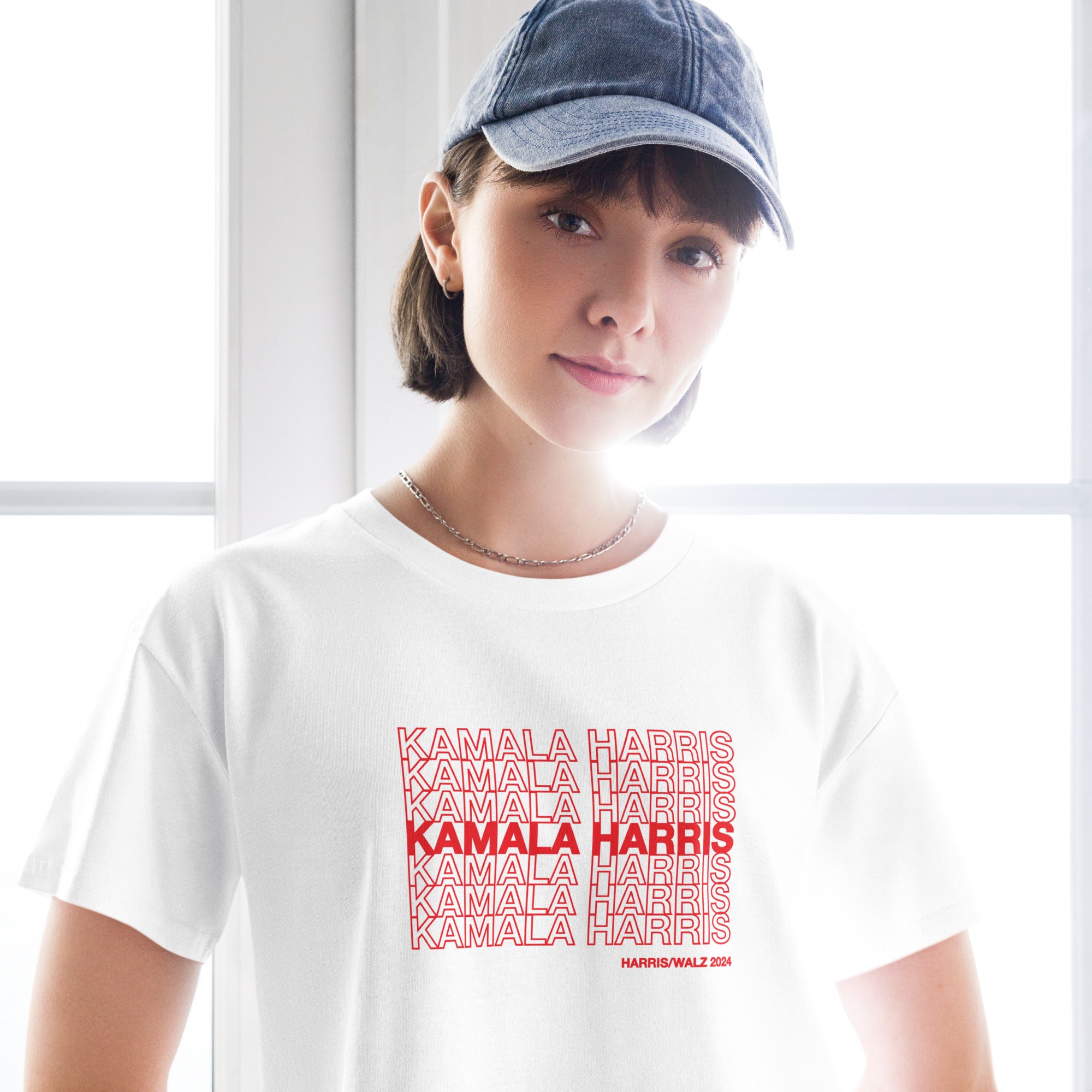 woman wearing White women's crop top t-shirt with red text saying "kamala Harris" in the classic plastic shopping bag design