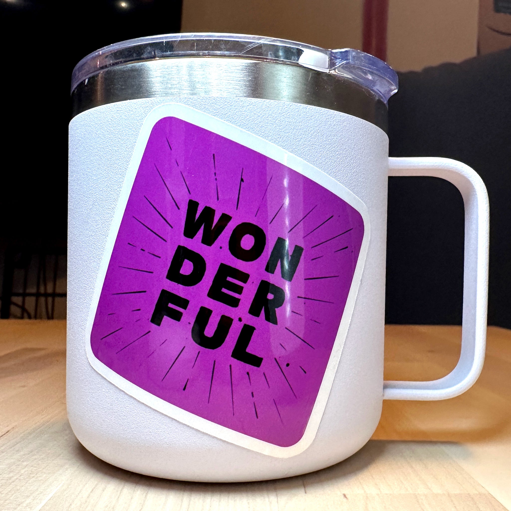 photo of waterproof vinyl sticker with the word wonderful in 3 layers of black text on purple background on a white mug