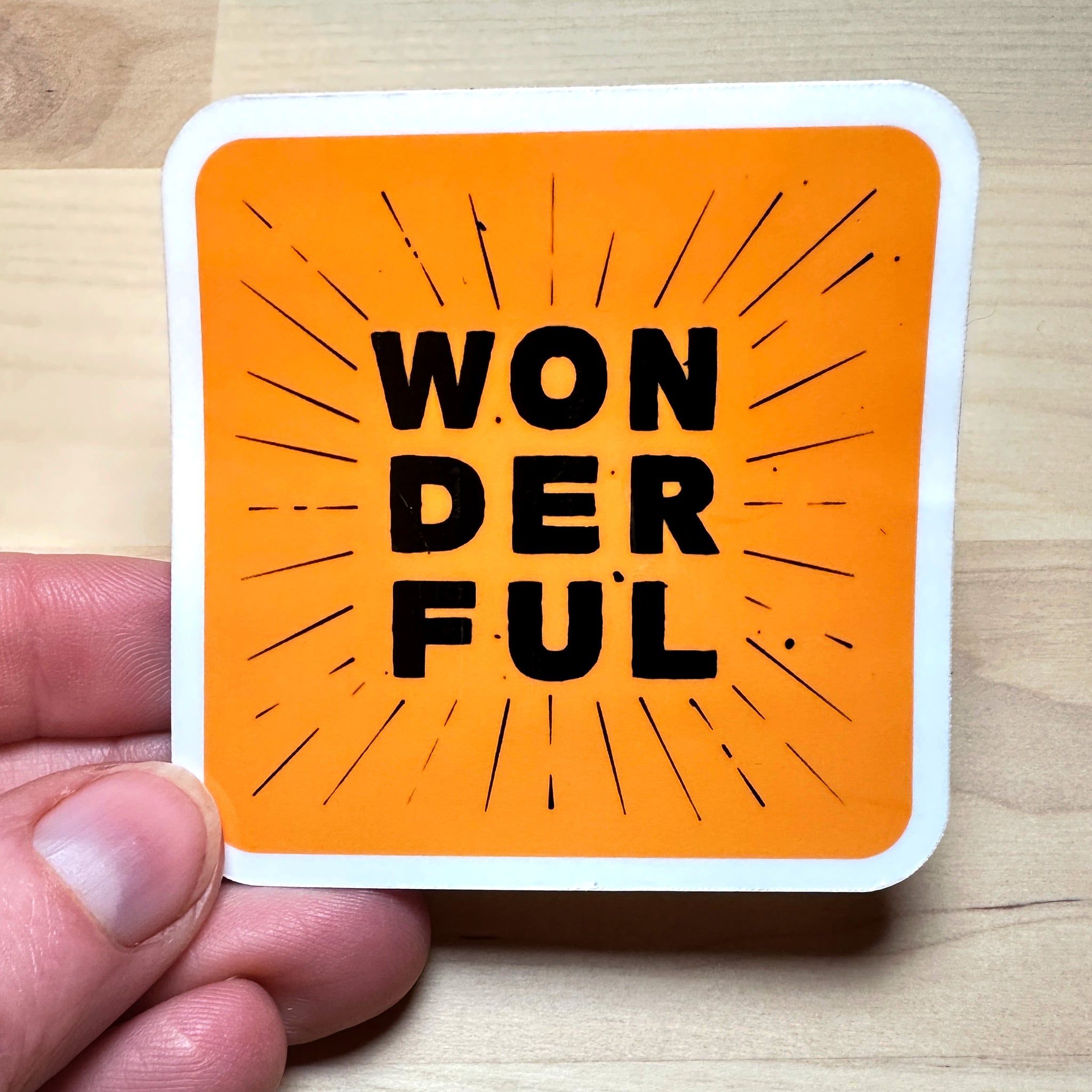 photo of waterproof vinyl sticker with the word wonderful in 3 layers of black text on orange background