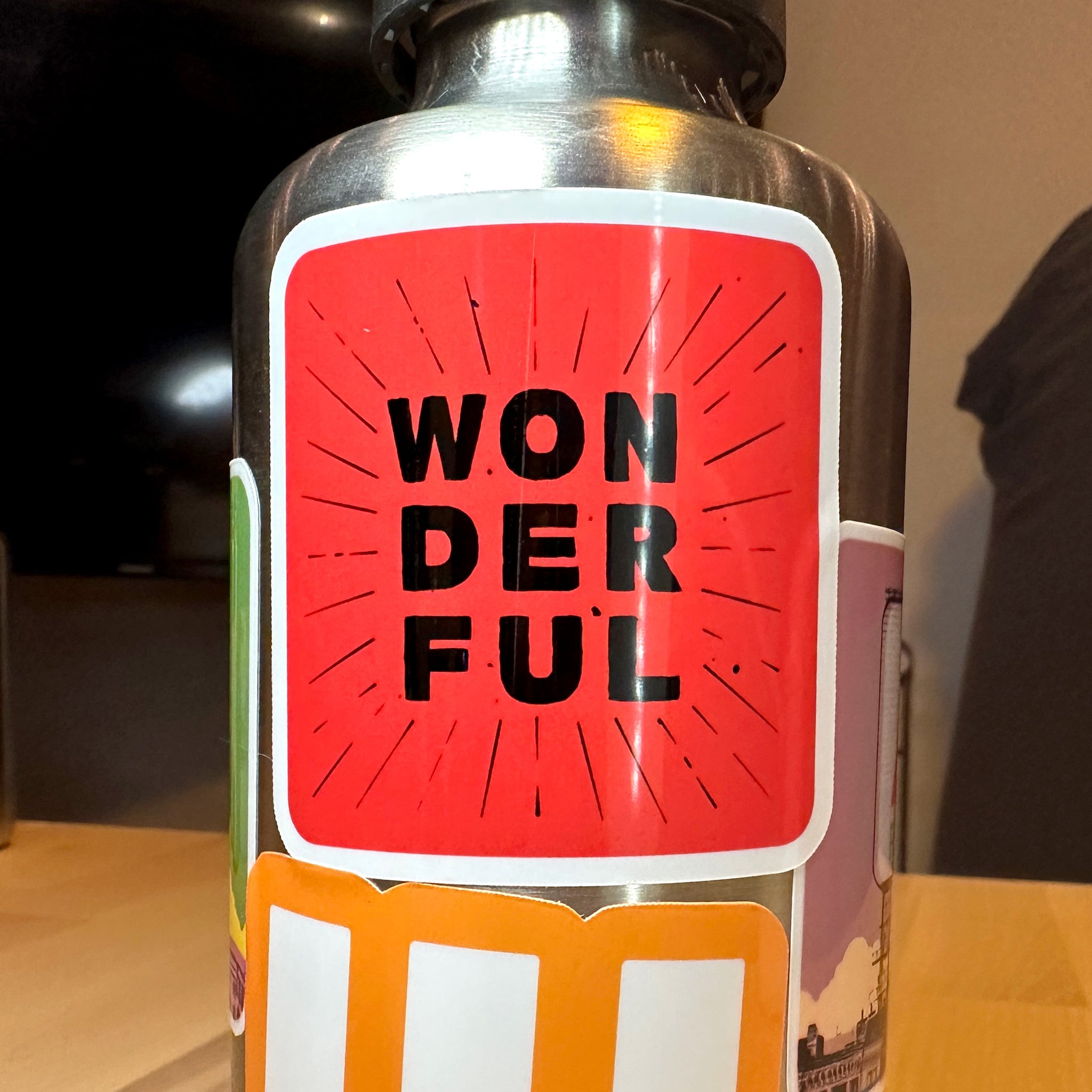 photo of waterproof vinyl sticker with the word wonderful in 3 layers of black text on red background on a metal water bottle