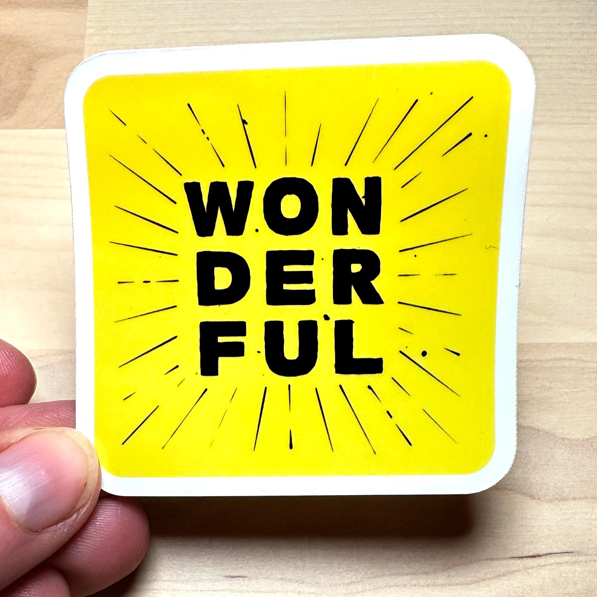 photo of waterproof vinyl sticker with the word wonderful in 3 layers of black text on yellow background